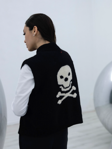 women wearing a knitted alpaca vest in black with skull and crossbones design a white background