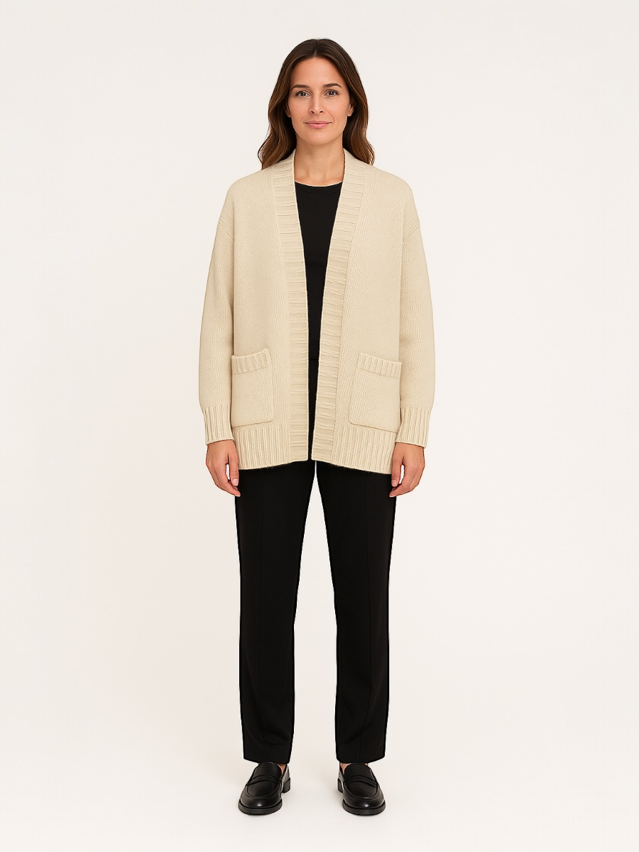 Woman wearing a beige cardigan over a black top and pants on a white background
