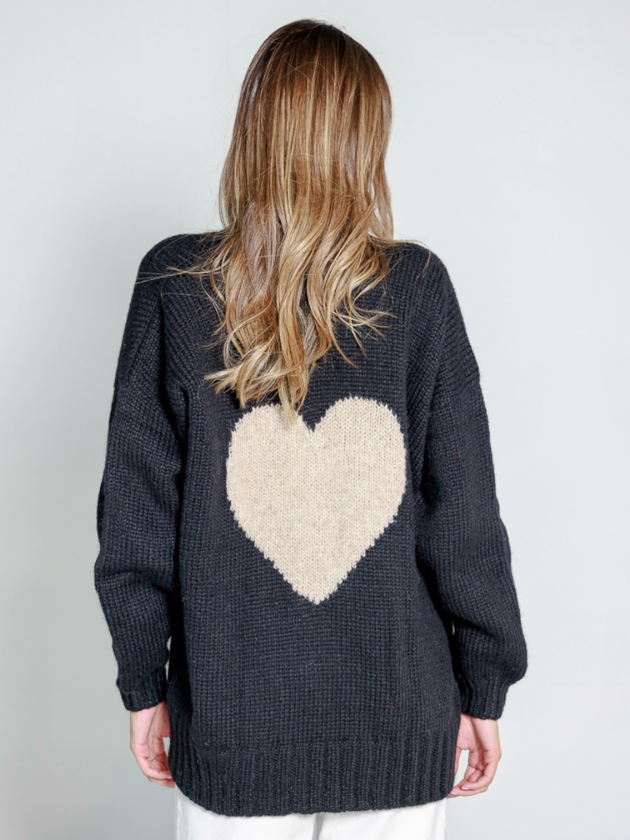Black alpaca sweater featuring an oversized white heart motif on the back, worn by a model in a white background