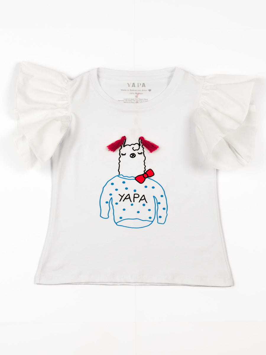 White cotton t-shirt featuring a playful embroidered alpaca motif with red tassel details, a red bow, and the word “YAPA” on the front and a ruffled design on the shoulders, shown here on a model