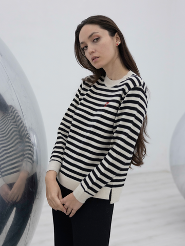 black and white stripped alpaca sweater with a red heart detail on a model with an art gallery background