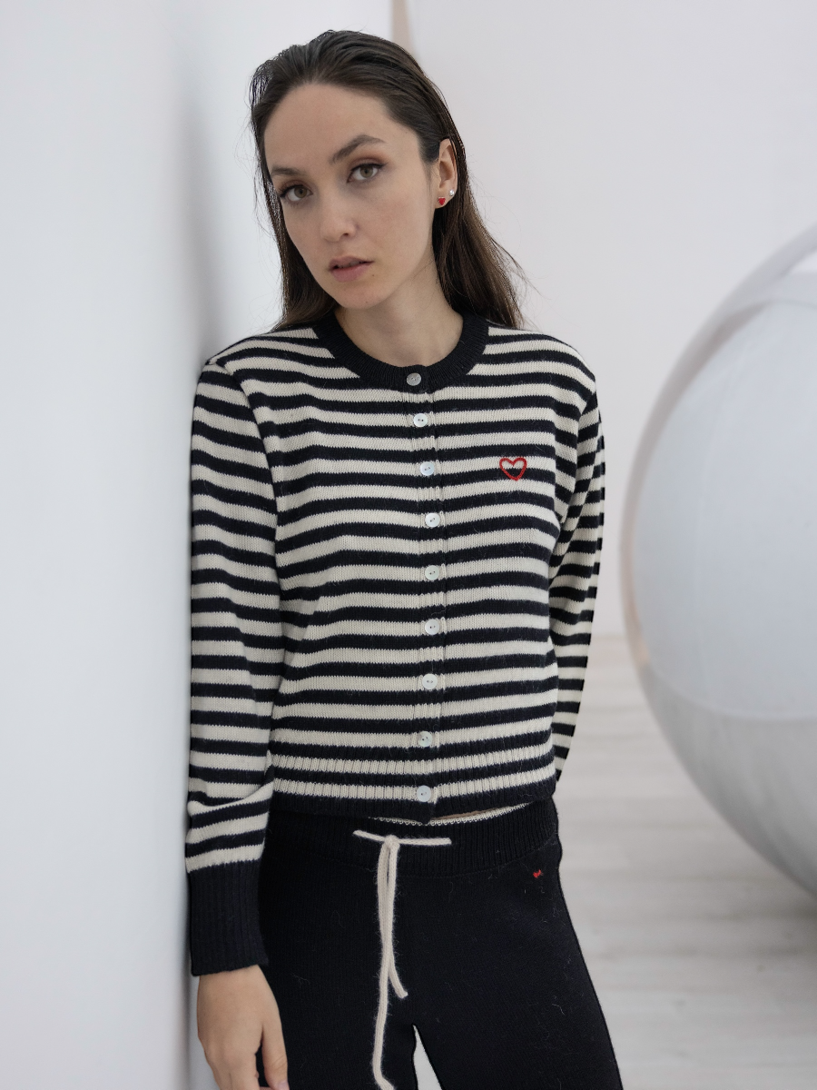 Woman wearing a black and white striped sweater with a red logo on a white background