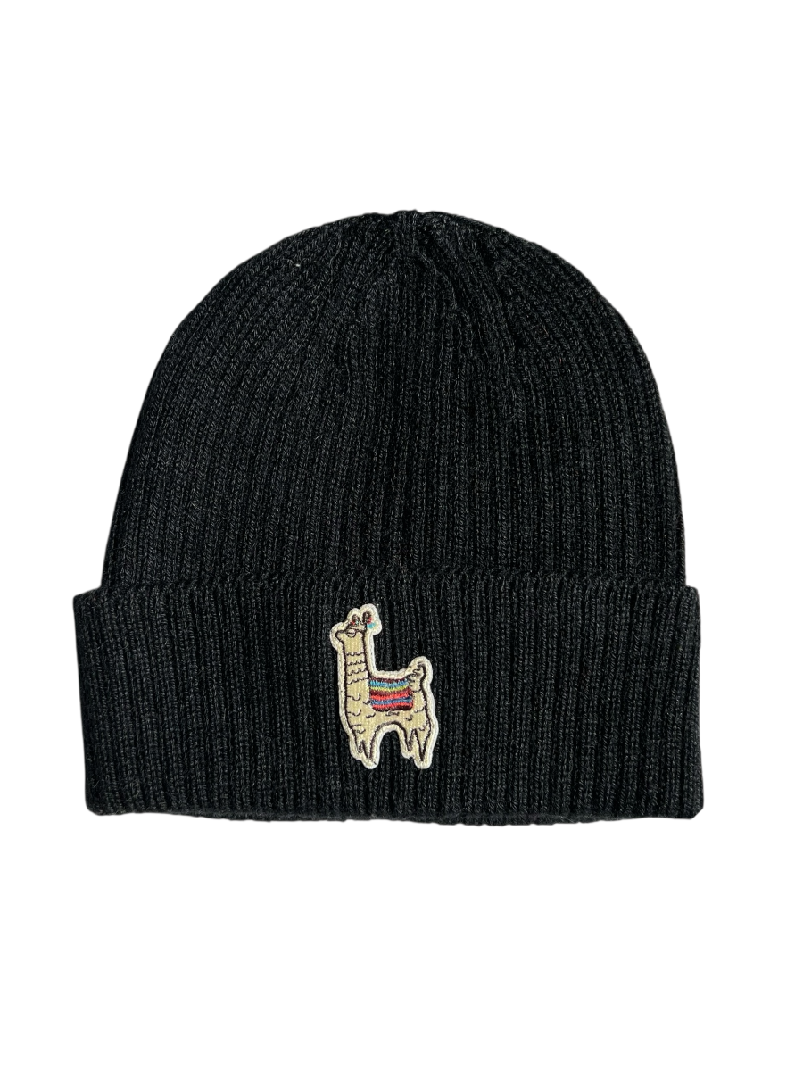Woman wearing a black knit beanie with a llama design outdoors