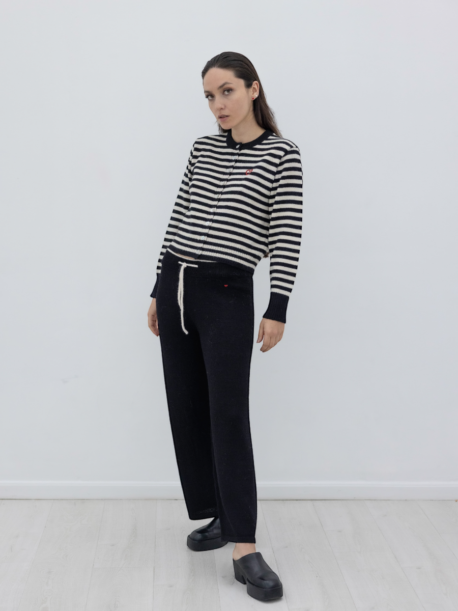Person wearing a black and white striped sweater and black pants against a white background