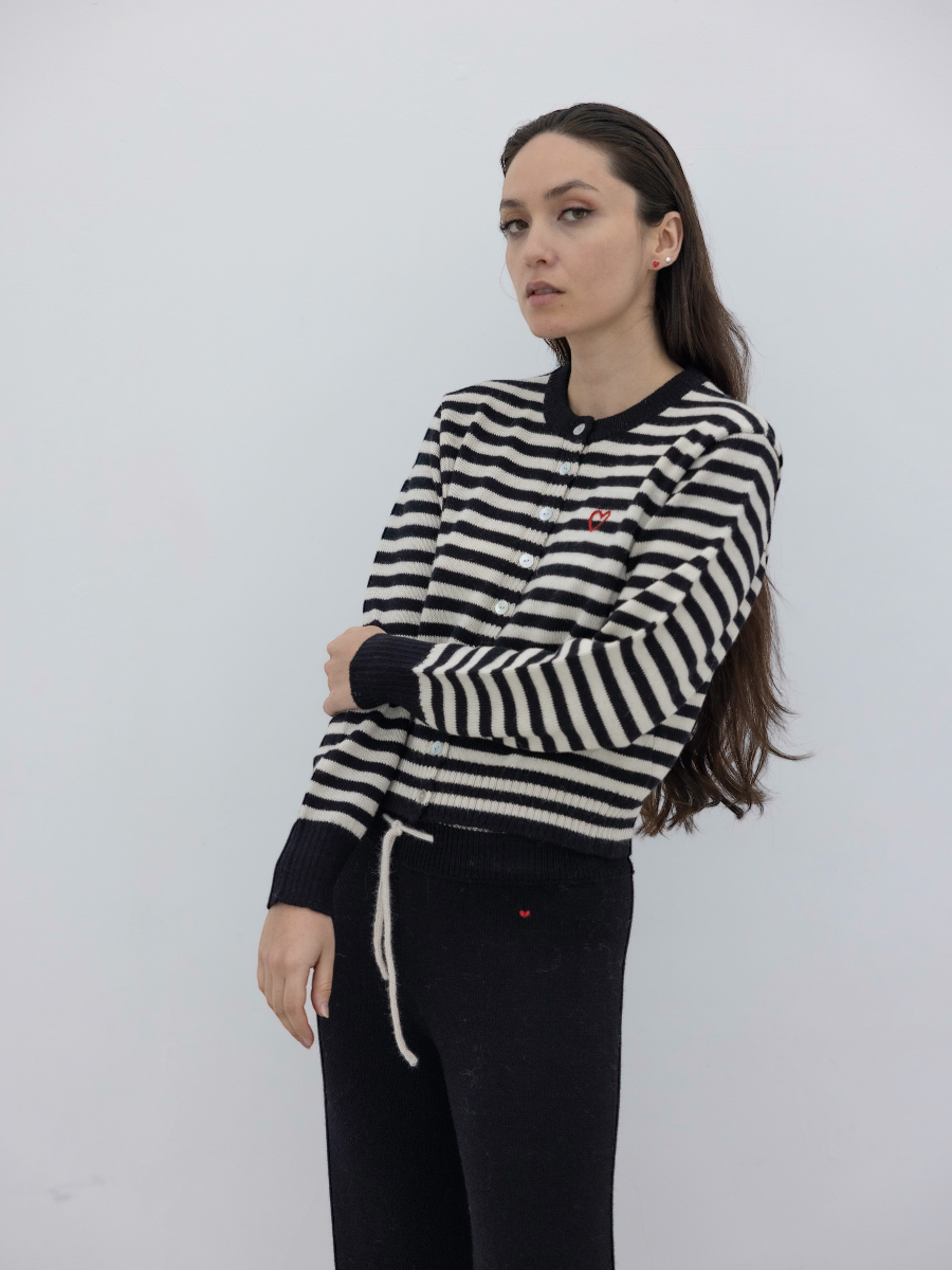 Woman wearing a black and white striped button up cardigan with a plain background