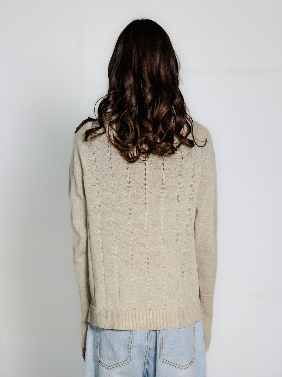 model wearing a white sweater against a plain background