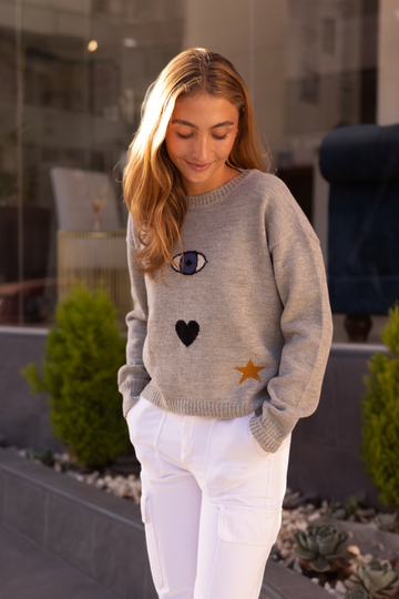 model wearing a grey sweater with an eye a heart and a star