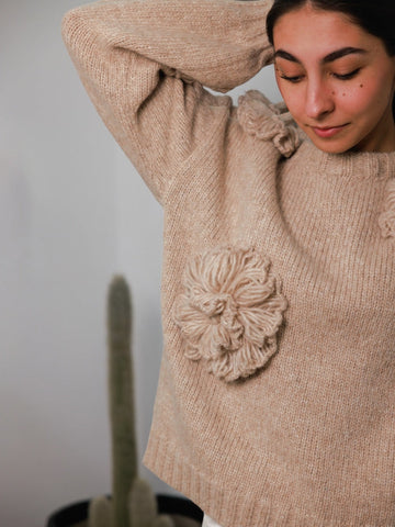 women wearing a beige alpaca sweater adorned with flower