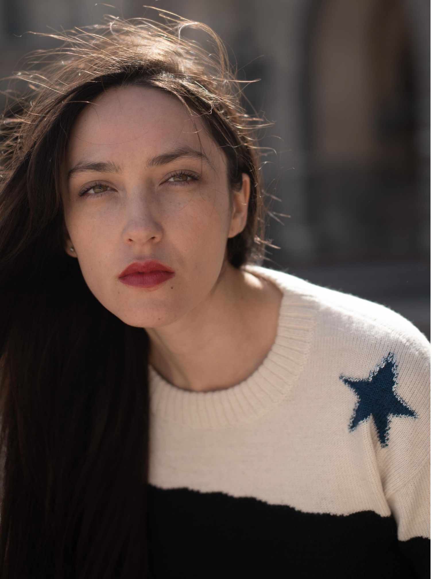 Woman wearing a sweater with a star design, looking off to the side.