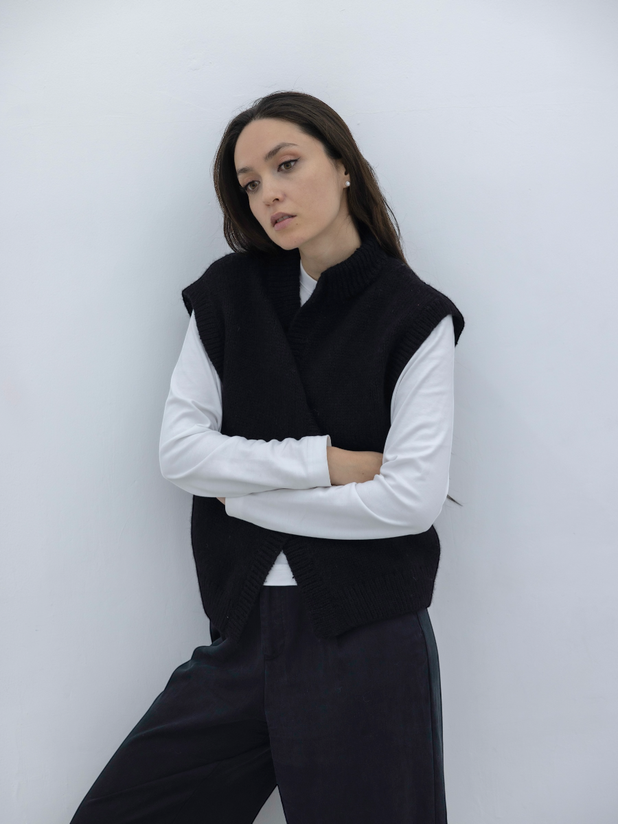 women wearing a knitted alpaca vest in black with skull and crossbones design a white background