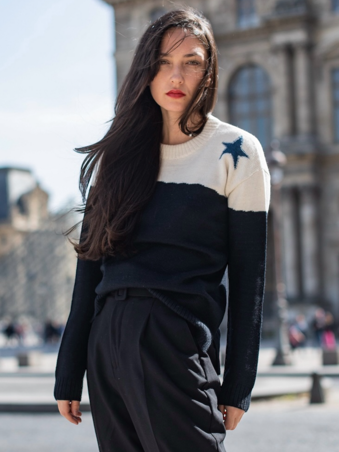 Woman wearing a black and white sweater with star design in an urban setting