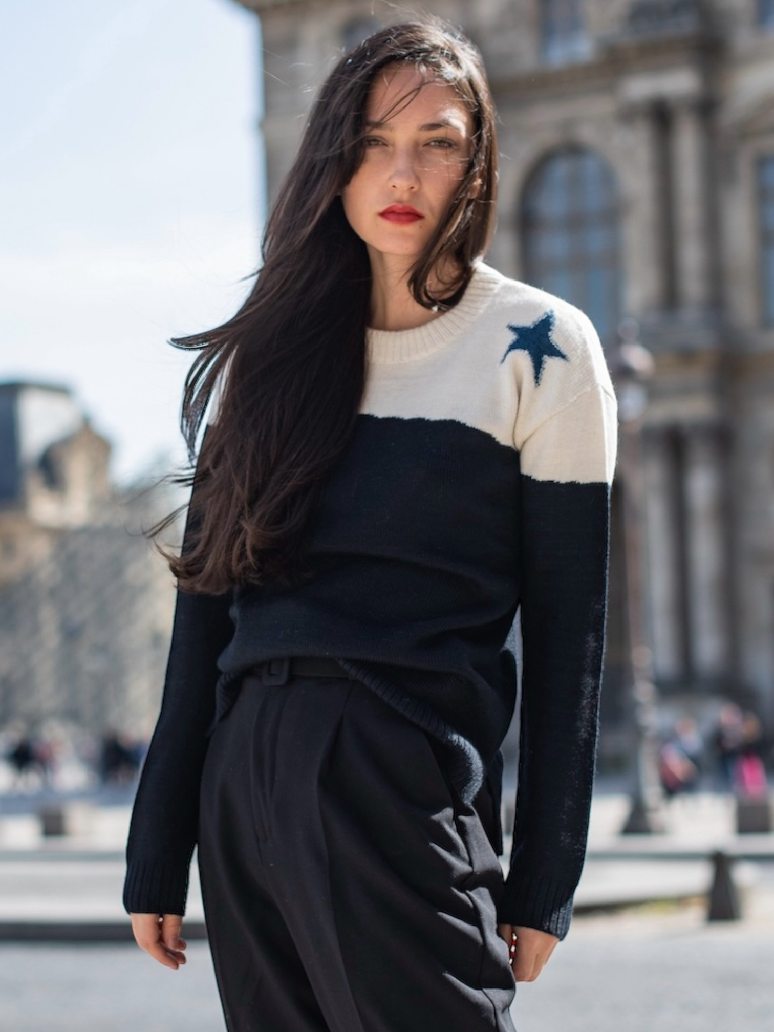 Woman wearing a black and white sweater with star design in an urban setting