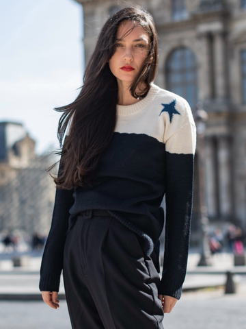 Woman wearing a black and white sweater with star design in an urban setting