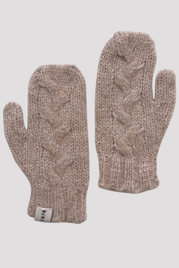 A pair of chunky cable-knit winter mittens in a heathered taupe-beige color, displayed against a solid light gray background. One mitten is shown palm-side and the other is shown finger-side, with a small white brand tag visible on the cuff.