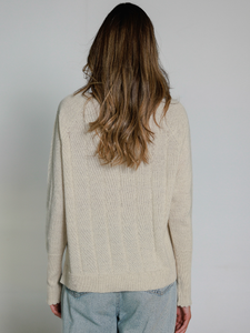 Person wearing a beige sweater with a plain background