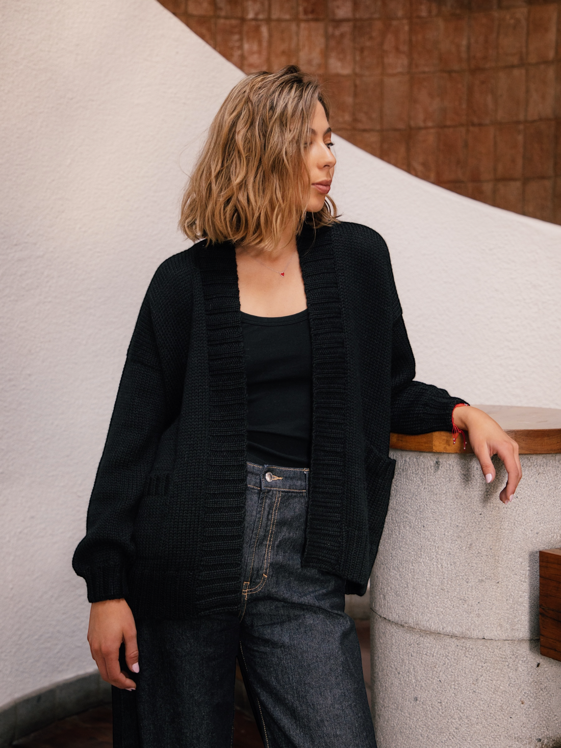 Woman wearing a black knitted cardigan with a red heart in the back walking around New York City
