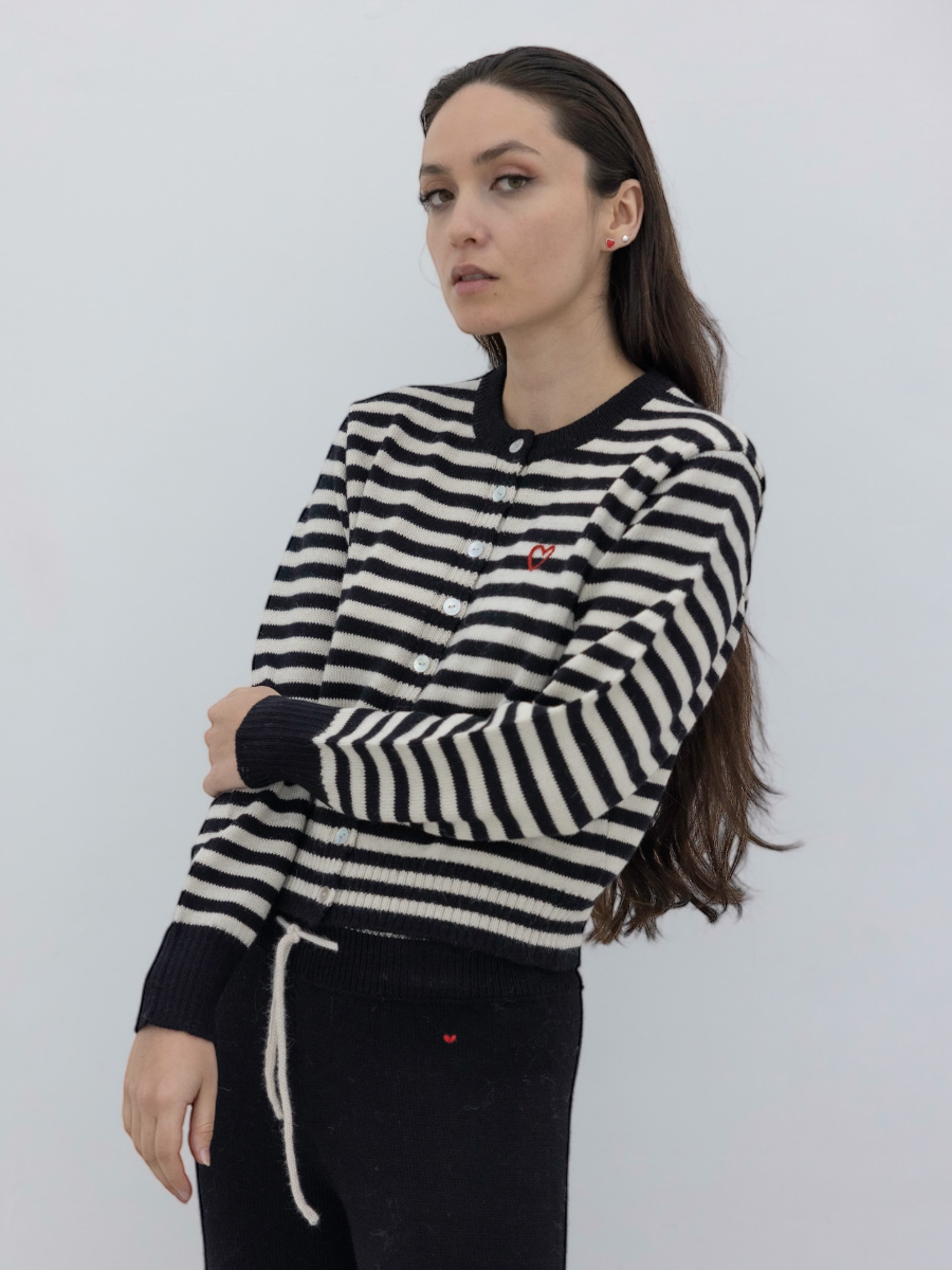 Woman wearing a black and white striped button up cardigan  with a plain background