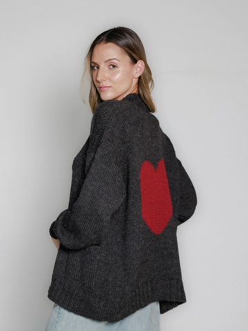 Dark grey alpaca sweater featuring an oversized burgundy heart motif on the back, worn by a model in a white background