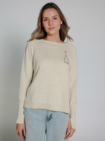 Woman wearing a white alpaca sweater with embroidered design of the Empire State Building and 'NYC' on a white background