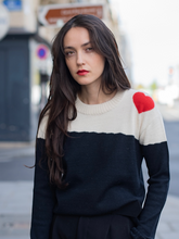 Load image into Gallery viewer, Dora sweater, baby alpaca, color-block black and white with red heart on the shoulder on model in city street 
