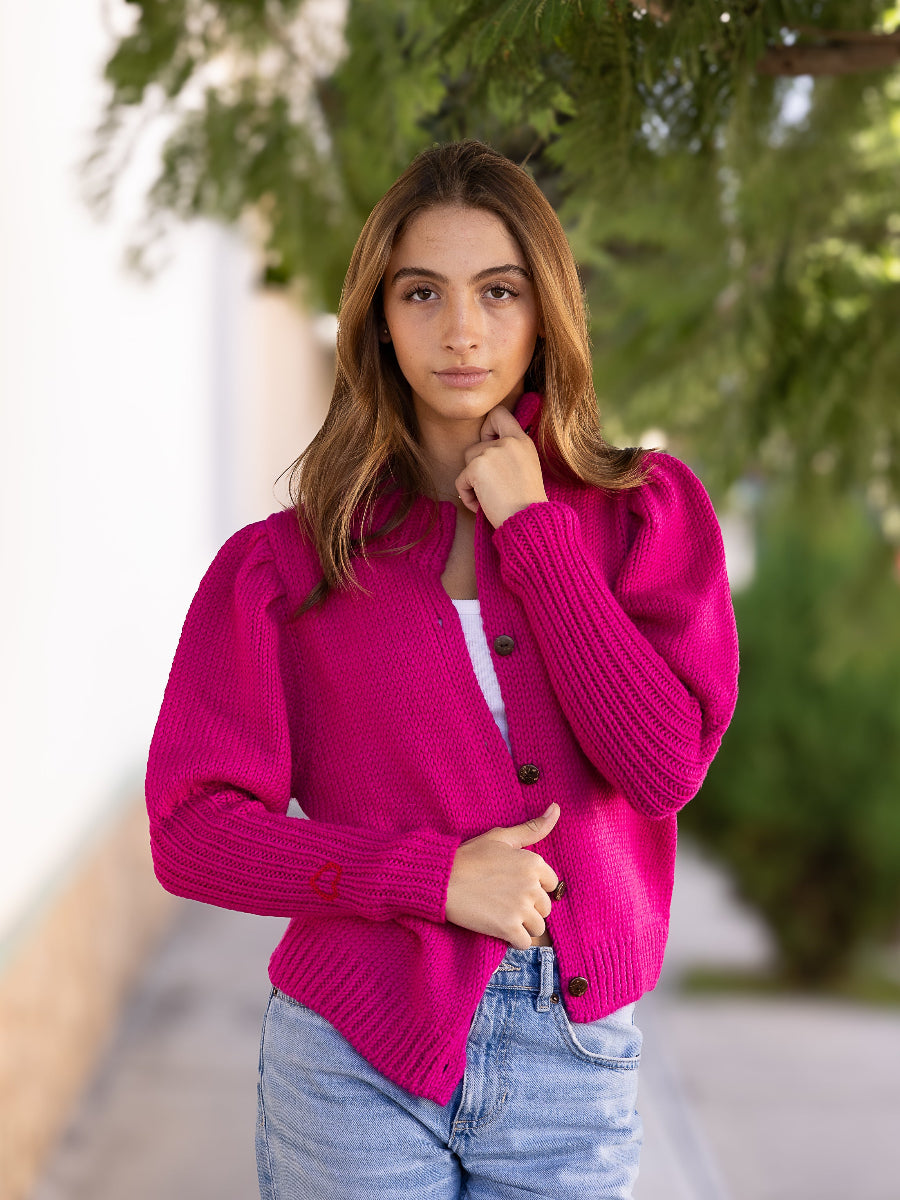 Hot pink alpaca cardigan featuring puffed sleeves, a ribbed high neckline, and a small red embroidered heart