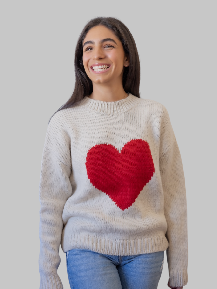 model wearing a white sweater with a red heart design against a plain background