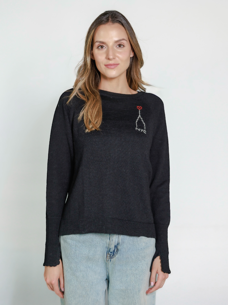 Woman wearing a black alpaca sweater with embroidered design of the Empire State Building and 'NYC' on a white background