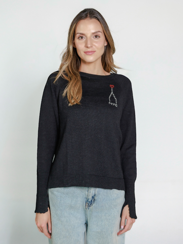 Woman wearing a black alpaca sweater with embroidered design of the Empire State Building and 'NYC' on a white background