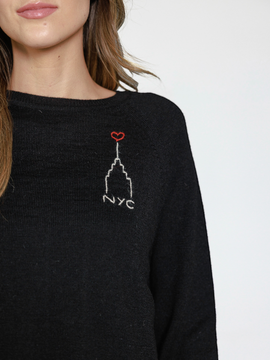 Black sweater with embroidered design of the Empire State Building and 'NYC' on a white background