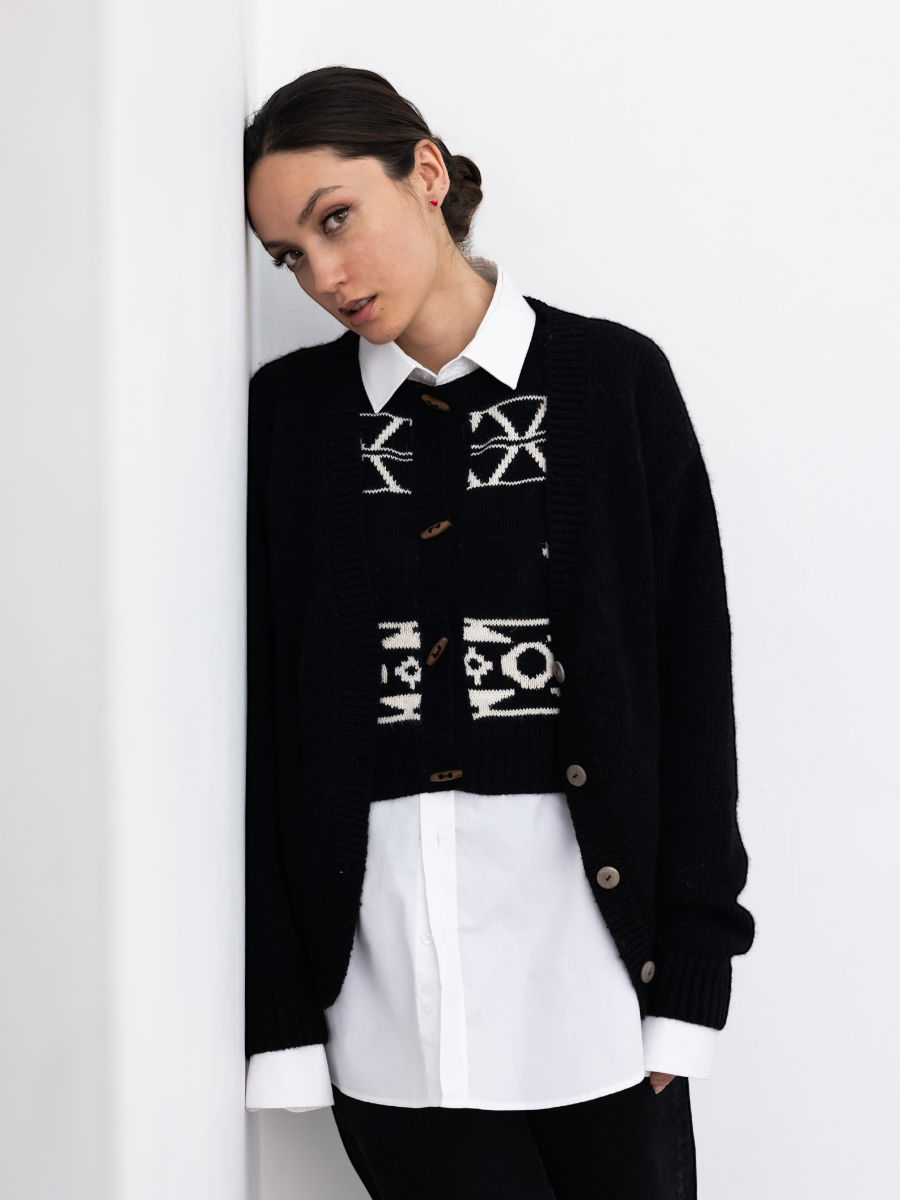 Person wearing a black sweater with a skull design on the back against a white background