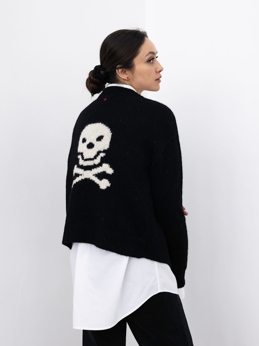 model wearing a black alpaca chunky sweater with a skull design on the back against a white background