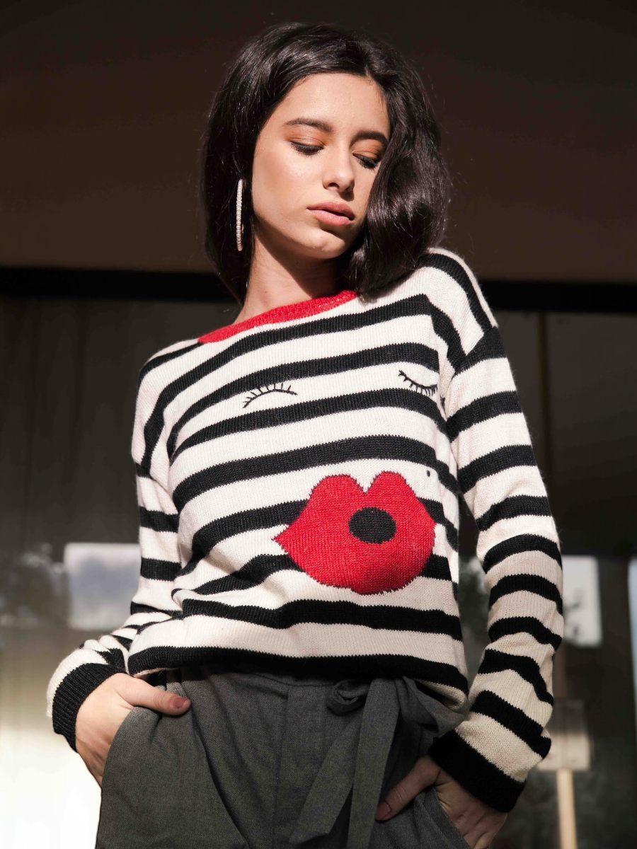 Person wearing a black and white striped sweater with red lips kiss design.