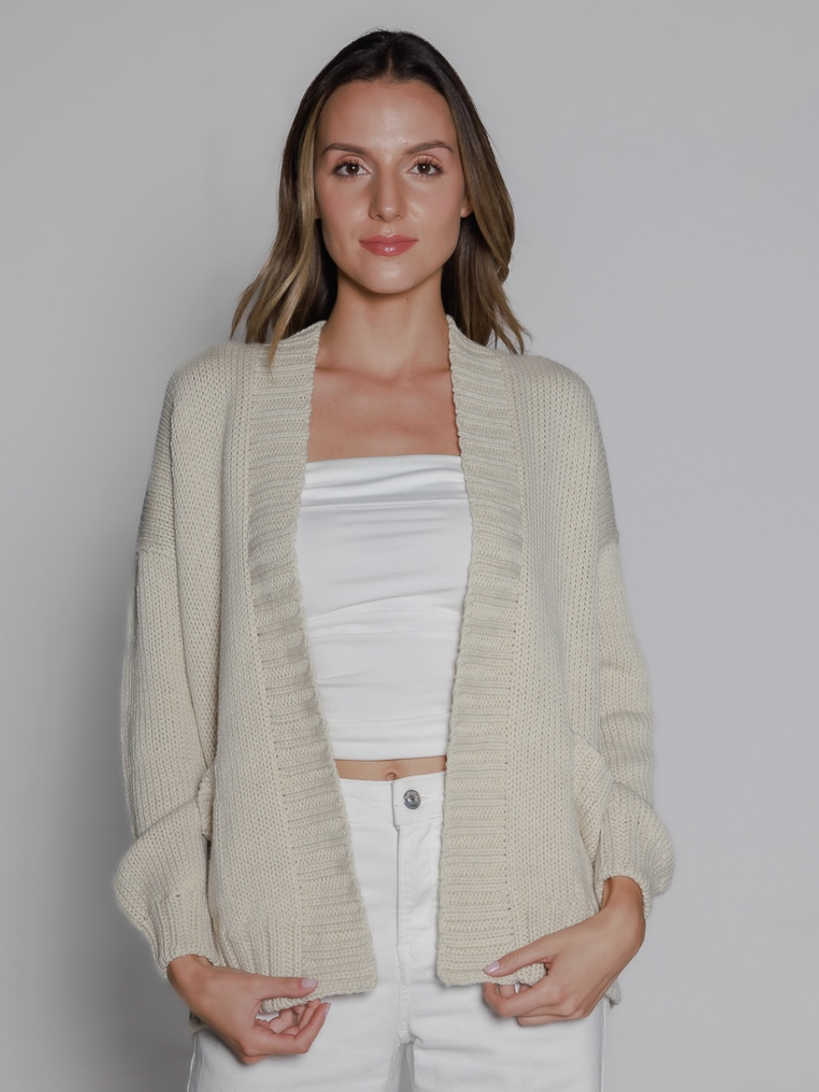 White alpaca cardigan white featuring a bold red “LOVE” motif with a heart design on the back, on a model in a white background.