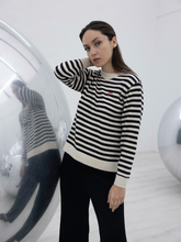 Load image into Gallery viewer, black and white stripped alpaca sweater with a red heart detail on a model with an art gallery background

