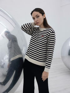 black and white stripped alpaca sweater with a red heart detail on a model with an art gallery background