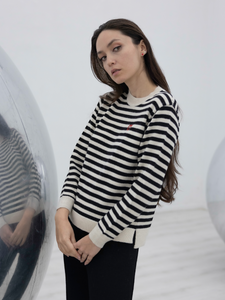 black and white stripped alpaca sweater with a red heart detail on a model with an art gallery background