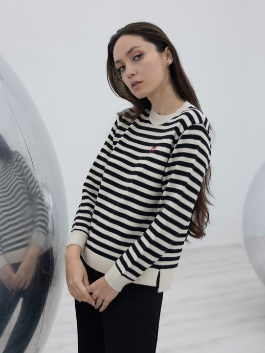black and white stripped alpaca sweater with a red heart detail on a model with an art gallery background