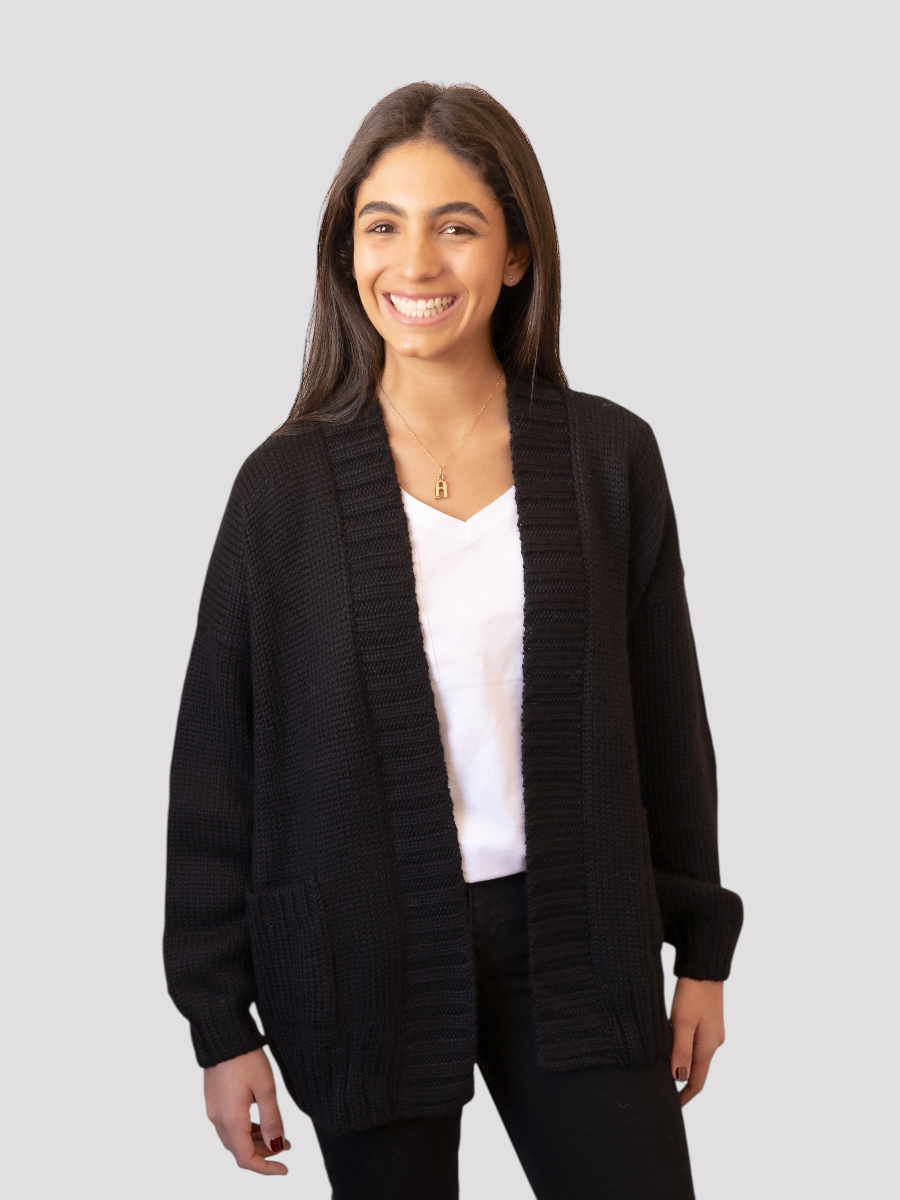Woman wearing a black cardigan over a white shirt on a light gray background