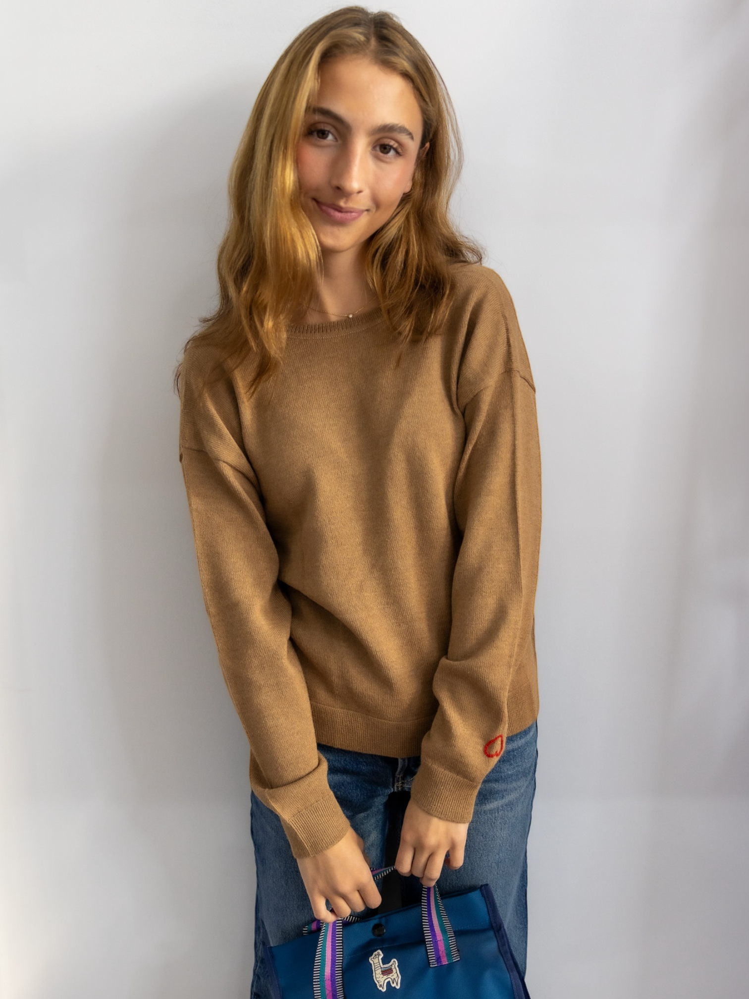 Woman wearing a camel alpaca v-neck sweater against a plain background