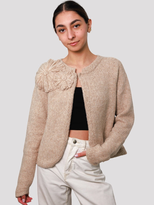 Woman wearing a beige knitted cardigan with a floral detail, alpaca cardigan 