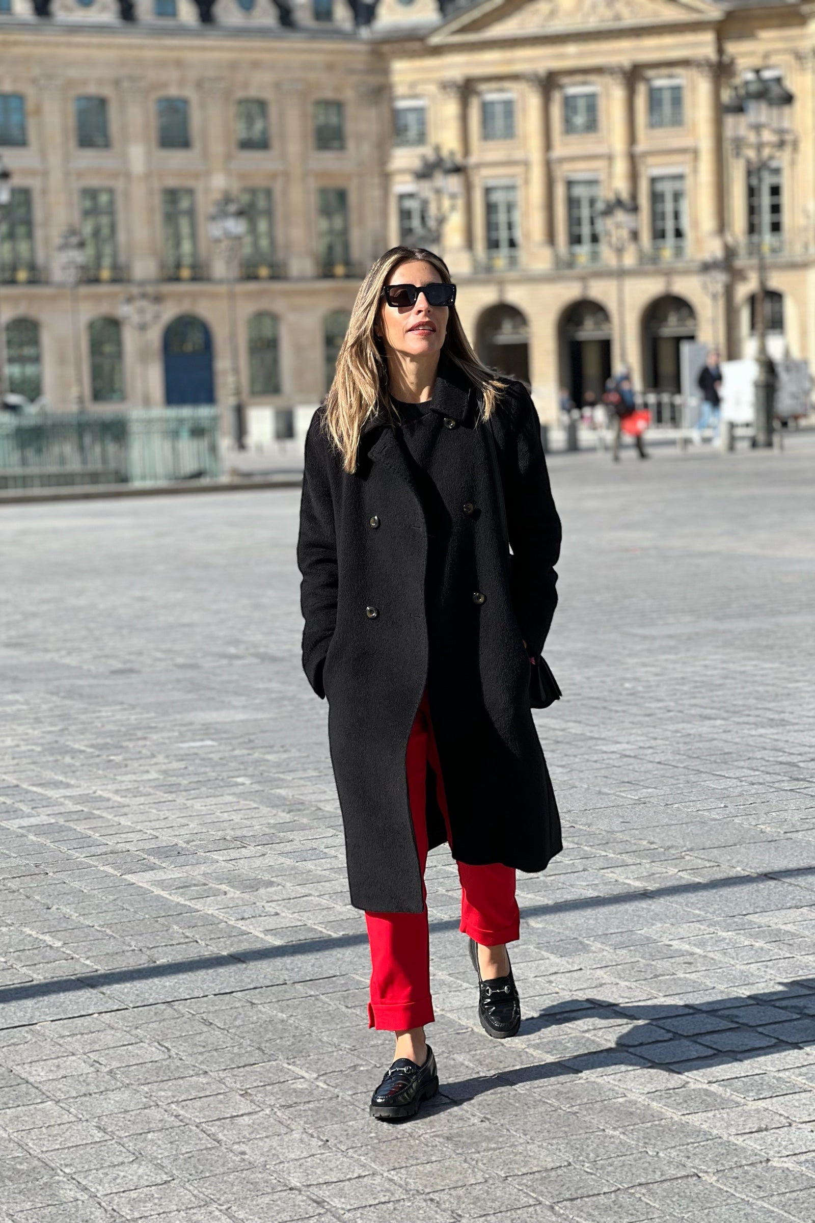 model wearing a black alpaca  coat double button long with city view background