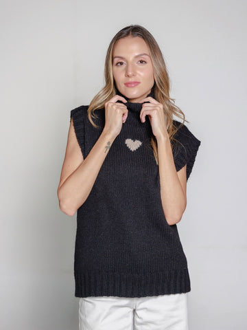 Woman wearing a black alpaca knitted sweater vest against a plain background