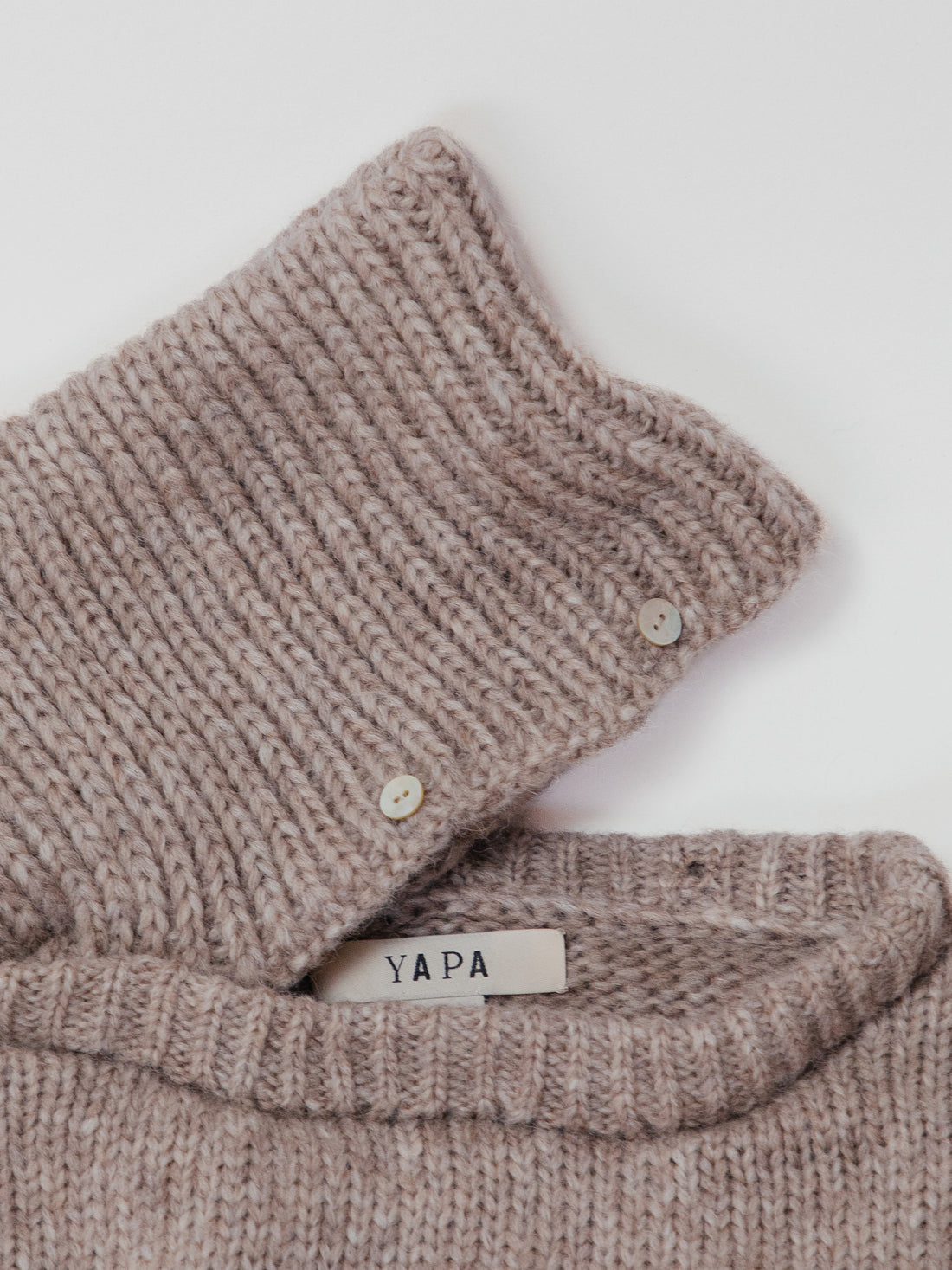 Knitted neck warmer with a 'Yapa' label on a white background