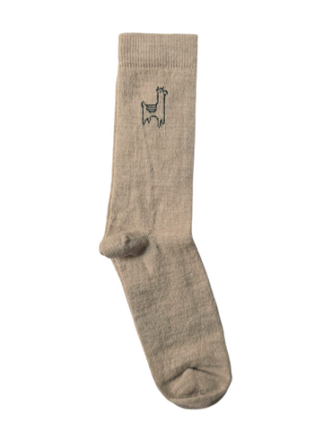 A pair of beige alpaca socks with a small alpaca yapa logo on the ankle area.