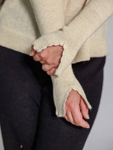 Cargar imagen en el visor de la galería, Close-up of a person wearing a beige sweater with lace cuffs on a plain background

