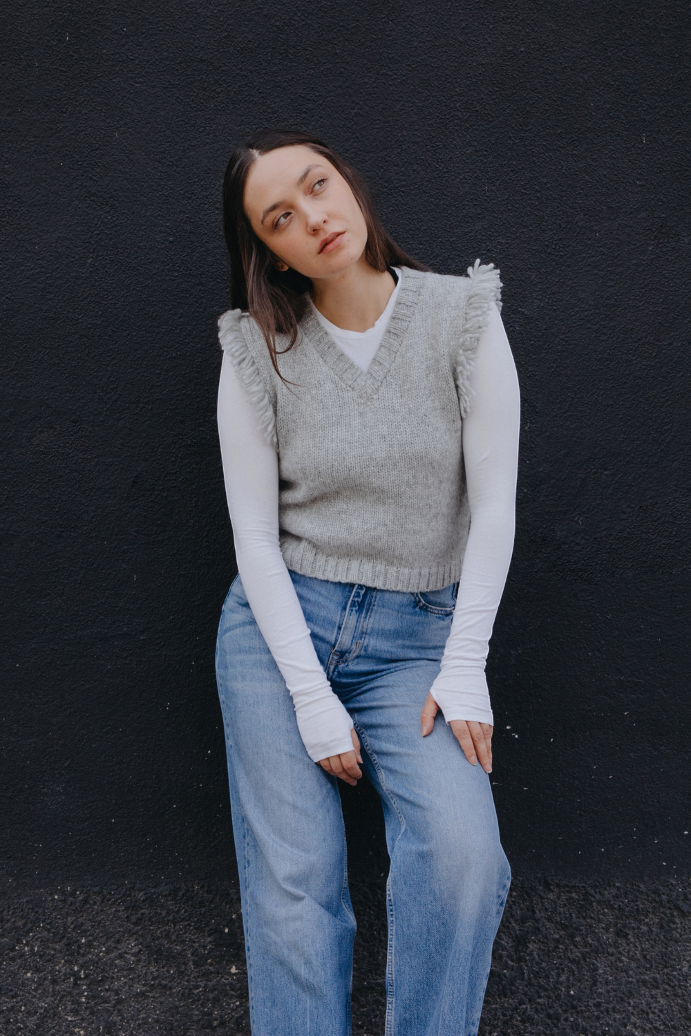 A light gray knit sweater vest with fringed sleeve edges and a V-neck, laid flat against a light gray background. The brand label reads Yapa