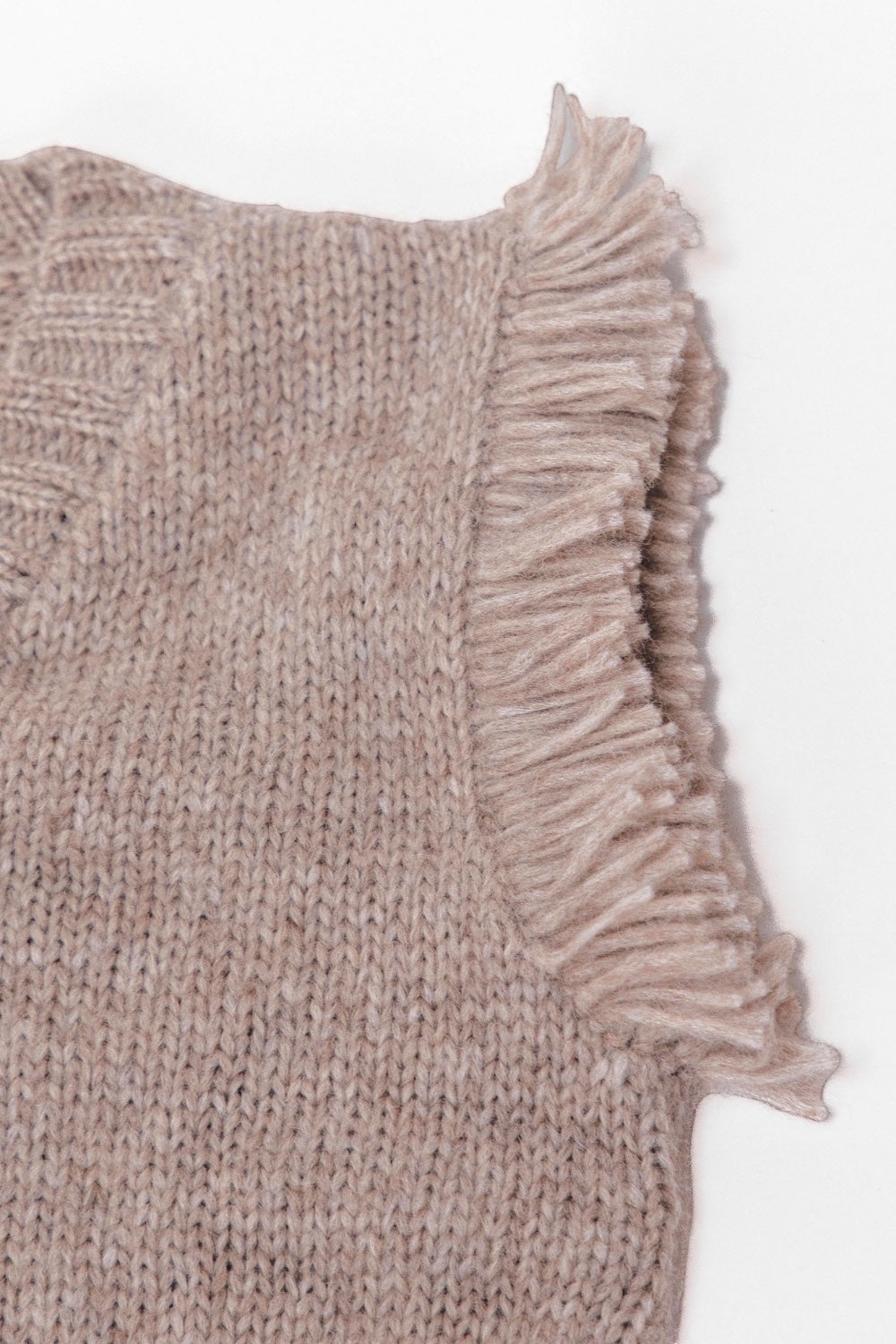 Close-up of a light gray knit sweater vest with fringes