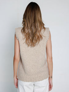 women wearing a beige sleeveless knitted vest against a plain background