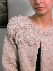 Beige knitted cardigan with floral embellishments.