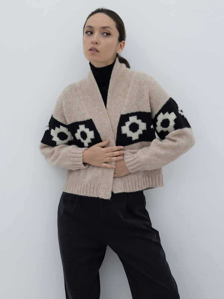 beige llama cardigan with black and white cross pattern, worn by a model on a plain background